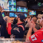 Image of guys in a sportsbar looking at a monitor and clapping